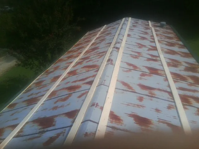 Rusted metal roof panels with new wood purlins before replacement — Storm Damage Roof Repair in Stout by Roofing Brothers