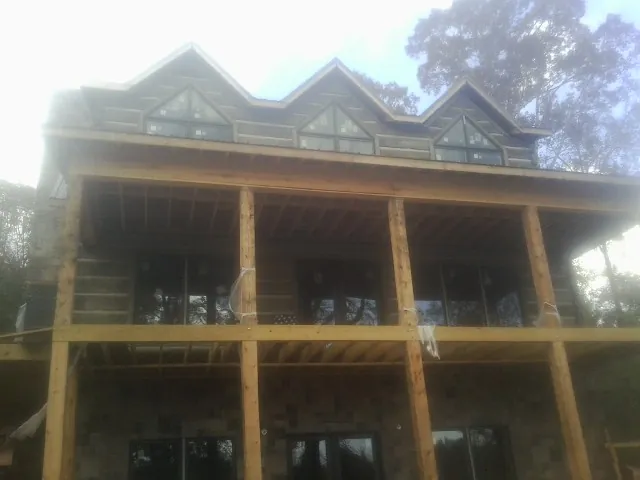 Dormers and porch framing on a large log home under construction — Roof Coating work by our crew in Stout