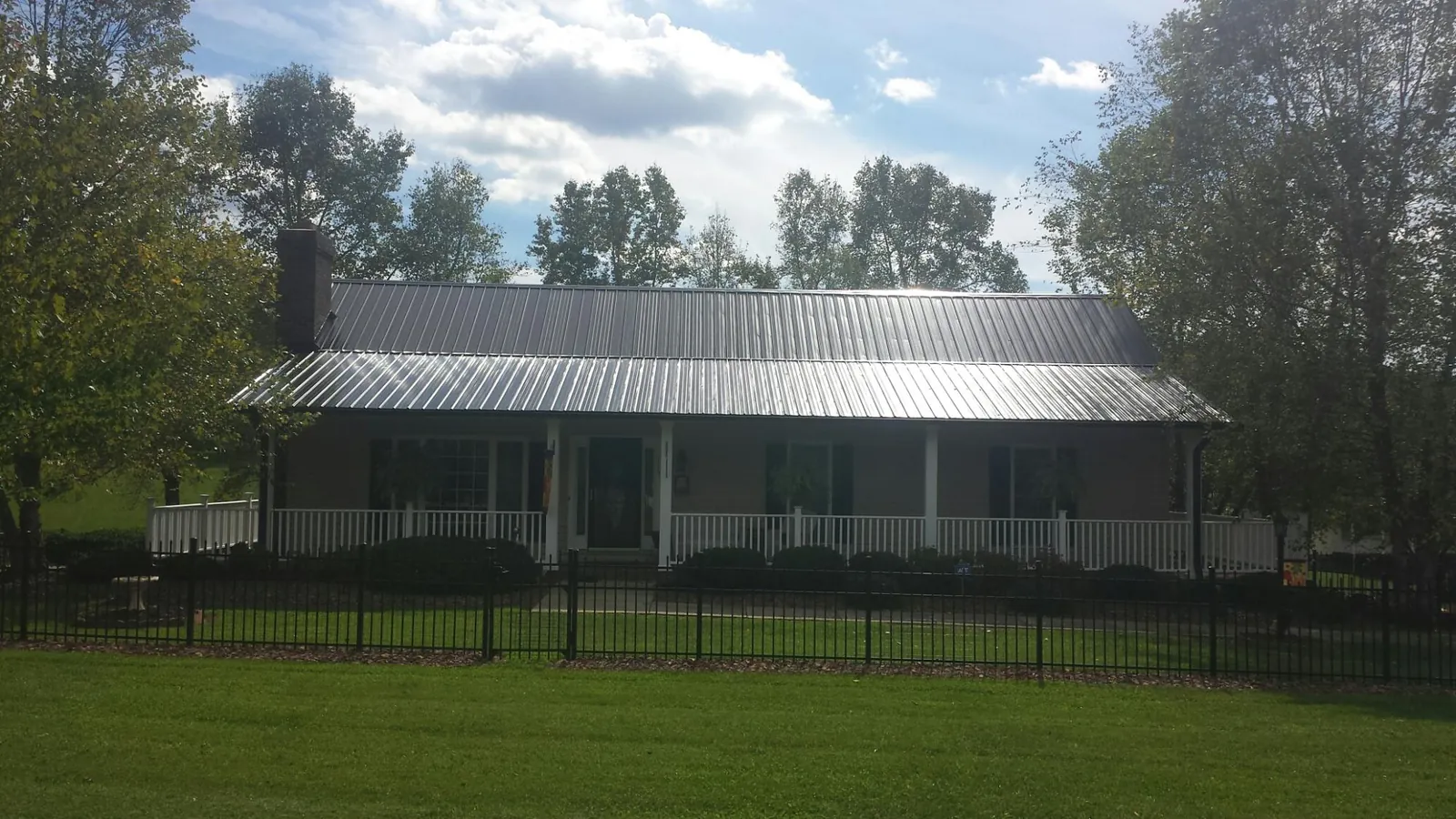 Gray metal roof on a brick ranch with a full width front porch — Gutter Guard Installation work by our crew in Stout
