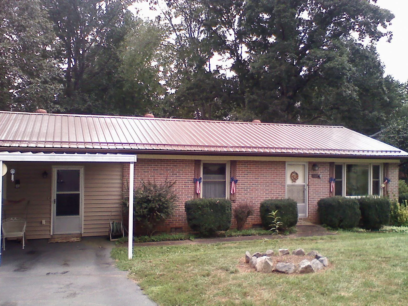 Bronze metal roof and carport on a brick ranch home — Roof Repair work by our crew in Stout