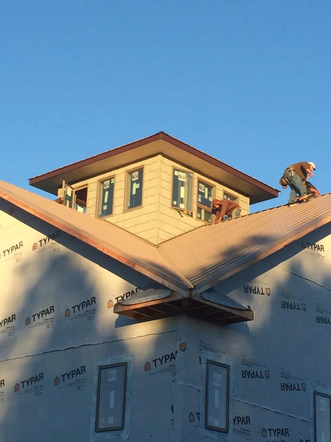 Roofers working around a rooftop cupola on a new metal roof at sunset — Roof Waterproofing in Stout by Roofing Brothers